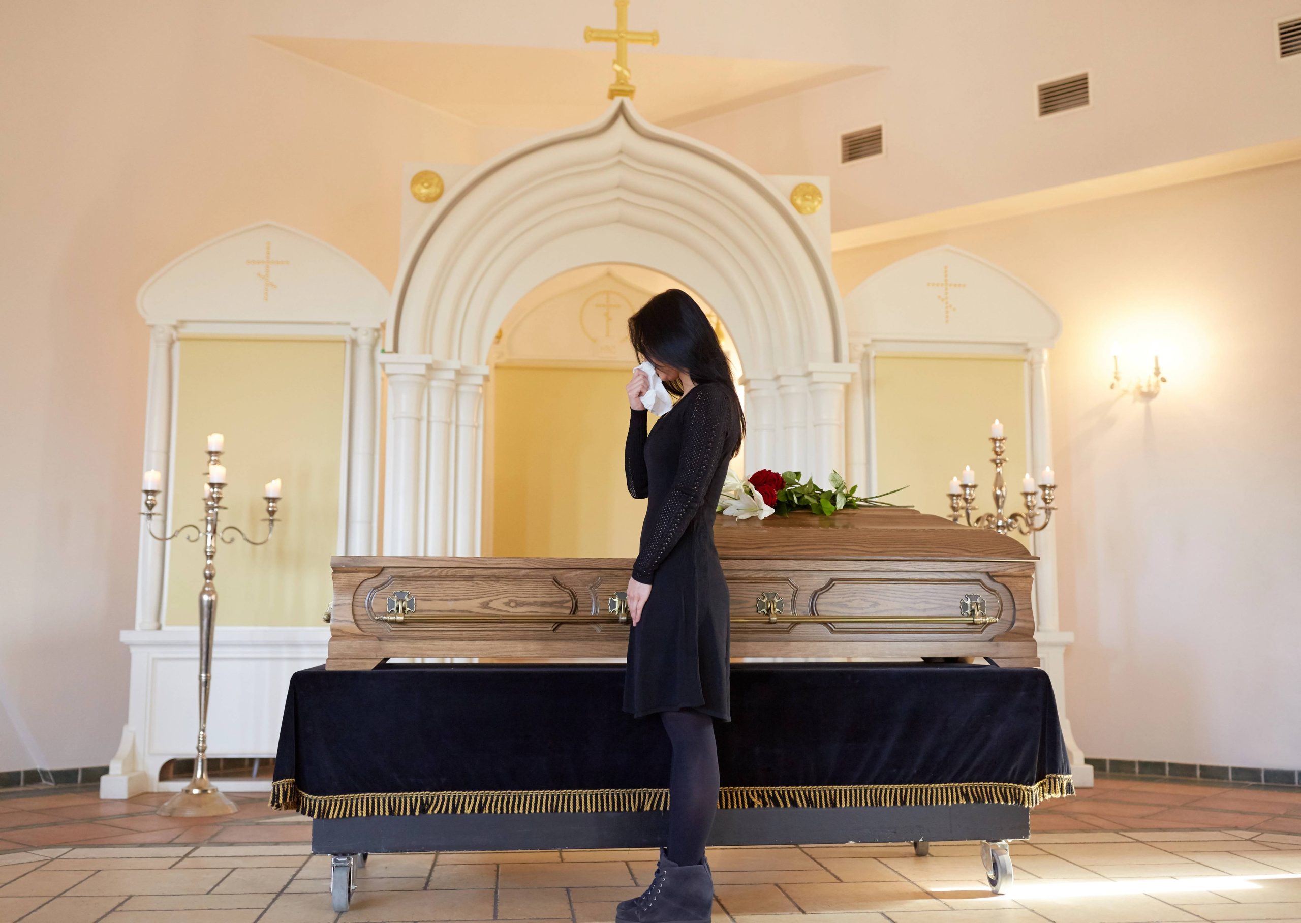 אישה אבלה ליד ארון קבורה בטקס פרידה מכובד, עלי שלכת, שירותי אופרה, רגע של אבל – אישה בלבוש שחור ליד ארון קבורה, כשמישהו נפטר,